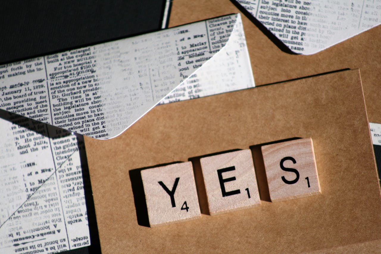 Close-up of Scrabble letters spelling YES on a vintage-style envelope for invitation or message.